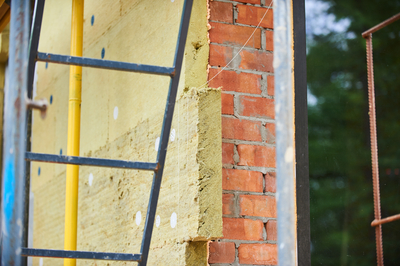 Plaques isolantes jaunes posées sur un mur en briques lors d'une isolation extérieur.