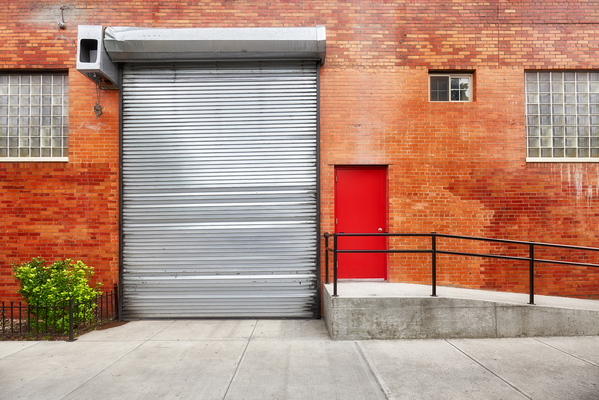 Porte de garage isolante à côté d'une porte de garage enroulable.