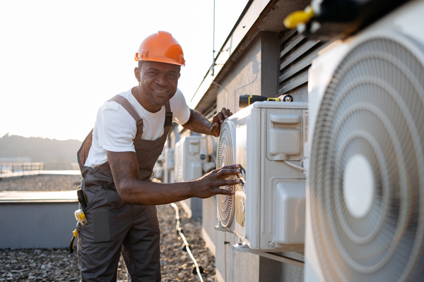 Installateur pompe à chaleur devant plusieurs unités extérieures.